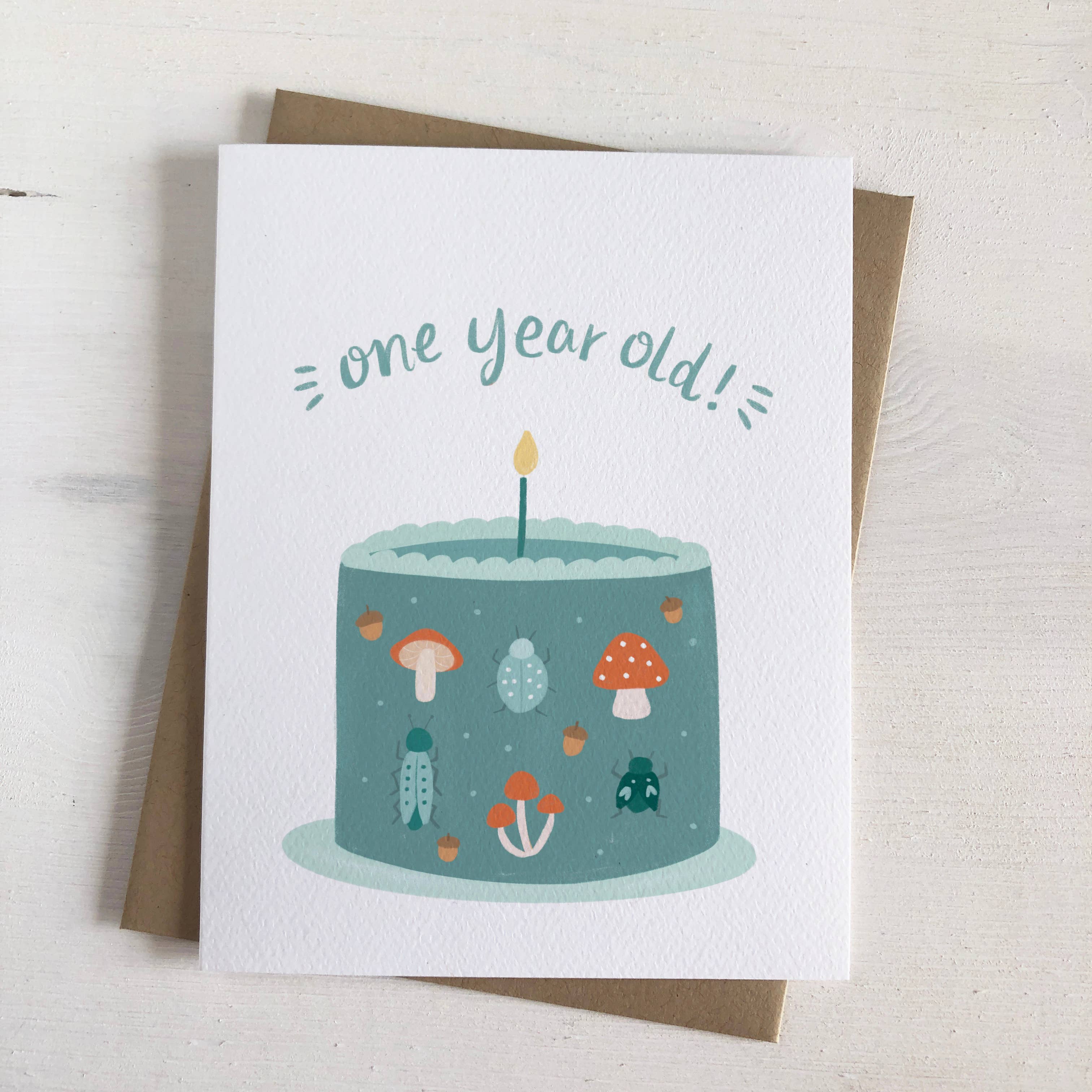 Greeting card with a birthday cake illustration and 'one year old!' text on a white background.