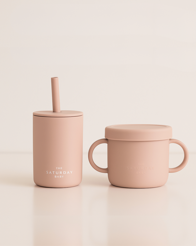 Two pink silicone cups with lids on a beige background